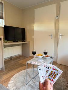 a person holding up a card game with two glasses of wine at Chalet Boerennest bij strand en duinen - Midicamping Van der Burgh - Rockanje in Rockanje