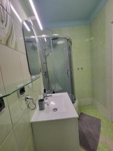 Un baño con lavabo y ducha con espejo. en Nowa Apartment, en Wroclaw