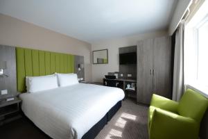a hotel room with a large bed and a chair at Holiday Inn Wolverhampton - Racecourse by IHG in Wolverhampton +44 photos