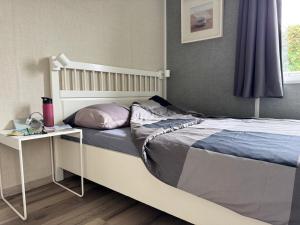a bedroom with a bed with a nightstand next to it at Chalet Boerennest bij strand en duinen - Midicamping Van der Burgh - Rockanje in Rockanje