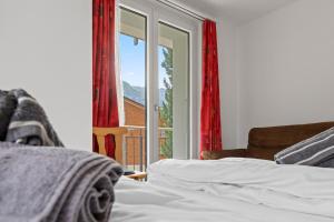 a bedroom with a bed and a window with red curtains at Zermatt 4 pers, 3 lits - vue & calme in Zermatt