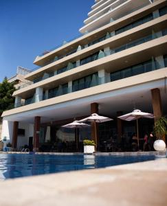 Ein Hotel mit Tischen und Sonnenschirmen neben einem Pool in der Unterkunft Lujoso Dpto vista a ciudad Edificio Poseidón in Manta