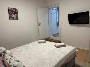 a bedroom with a bed and a flat screen tv at Apartman Kraljević in Ljubuški