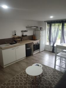 una cucina con armadi bianchi e un tavolo di Appartement Noméo a Saint-Privat-des-Vieux