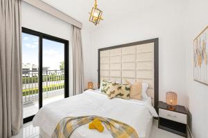 um quarto branco com uma cama grande e uma janela em Damac Hills 2 Poolside no Dubai mais 37 fotografias