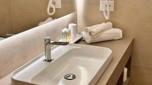 a bathroom with a sink and a mirror and towels at Hotel Villa Cedrino in Dorgali