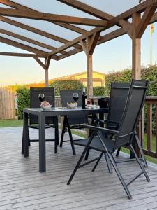 a black table and chairs on a deck with a pergola at Chalet Boerennest bij strand en duinen - Midicamping Van der Burgh - Rockanje in Rockanje