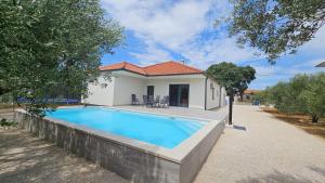 a swimming pool in front of a house at Martha's Oliveyard in Biograd na Moru