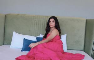 a woman in a pink dress sitting on a bed at Valley View at Twin Oaks in Dharampur