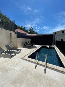 a swimming pool on a patio with chairs and an umbrella at Apartmani Villa Antea in Klek