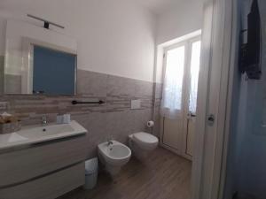 ein Badezimmer mit Waschbecken, Toilette und Spiegel in der Unterkunft S'Istella Affittacamere in Tinnura