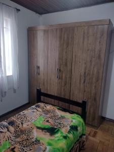 a bedroom with a bed and a large wooden cabinet at Casa de hospedagem in Blumenau