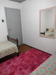 a bedroom with a mirror and a bed and a rug at Casa de hospedagem in Blumenau +1 photo