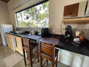 Una cocina con un mostrador con sillas y una ventana. en Chalé Causo Bão, en Gonçalves 35 fotos más
