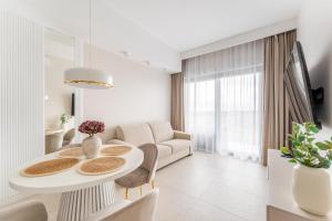 un soggiorno bianco con tavolo e sedie di Hevenia Mrzeżyno Apartament 74 Widok na Morze a Mrzeżyno