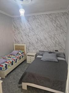 a bedroom with two beds and a stone wall at Younes Alkindi Nador in Nador