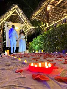 a man and woman standing in front of a stage with candles at Isla Bonita Zanzibar Beach Resort in Matemwe