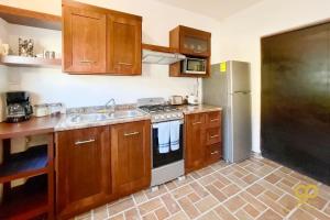 a kitchen with wooden cabinets and a stainless steel refrigerator at Chic Studio Kitchen WiFi TV Steps to Beach in El Centenario