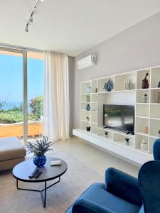 een woonkamer met een bank en een tv bij Mèla Twin Villa Green Coast in Himare