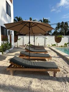 a row of lounge chairs with an umbrella next to a pool at Tumbili Hotel Boutique in Paje