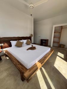 a bedroom with a large bed with a cat on it at Tumbili Hotel Boutique in Paje