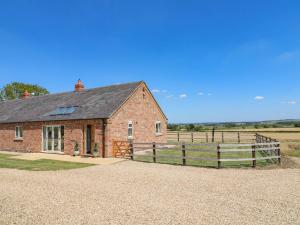 a brick house with a fence and a field at Teal Cottage in Melton Mowbray