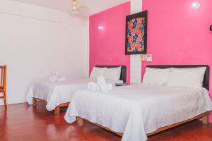 two beds in a room with a pink wall at Hotel Doña Mary Huatulco in Santa Cruz Huatulco +17 photos