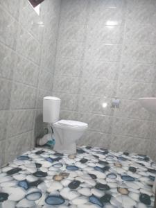 a bathroom with a toilet and a tiled floor at sopo's cottage in Kobuleti +13 photos