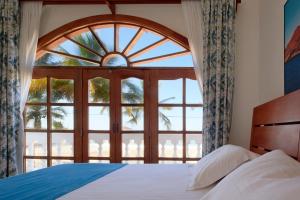 una camera da letto con un letto e una grande finestra di Hotel Albemarle Galapagos Beachfront a Puerto Villamil