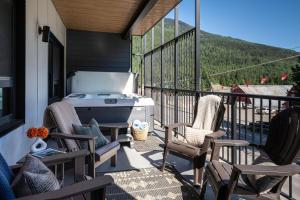 a patio with chairs and a grill on a balcony at Serenity Now by Revelstoke Vacations in Revelstoke
