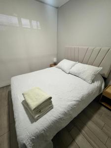 a bedroom with a white bed with towels on it at Moderno departamento a metros de Movistar Arena in Santiago +13 photos