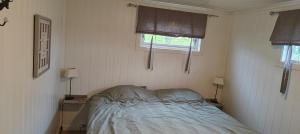 a small bedroom with a bed and two windows at Utsikten in Havningberg