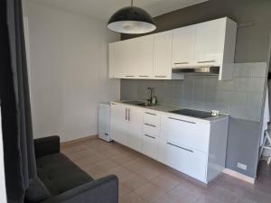 a kitchen with white cabinets and a couch in a room at La Casetta al Lago in Sorico