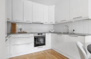 a white kitchen with white cabinets and a sink at Koselig leilighet in Arendal