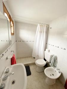 a white bathroom with a toilet and a sink at Hermoso departamento en Esquel, amplio y luminoso in Esquel