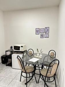 a dining room table with four chairs and a microwave at Suíte Central in Nova Friburgo