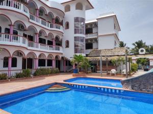 a hotel with a swimming pool in front of a building at Hotel Real del Quijote a sólo 50 metros de la playa in Tecolutla