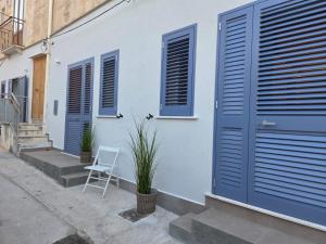 a white house with blue doors and a white chair at Al Vicolo FAVIGNANA CENTRO in Favignana +6 photos