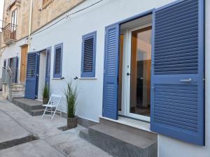 a house with blue shutters on the side of it at Al Vicolo FAVIGNANA CENTRO in Favignana