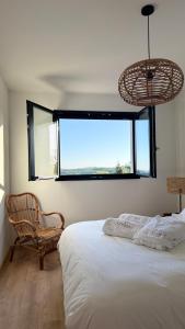 une chambre avec un lit, une chaise et une fenêtre dans l'établissement Maison avec Jacuzzi proche du lac, à Marcillac-la-Croisille