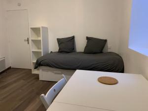 Un pequeño dormitorio con una cama y una mesa. en Studio rénové à 5 minutes du centre-ville, en Aire-sur-lʼAdour