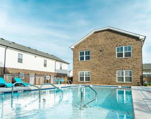 a swimming pool in front of a brick building at Arte Luxury Townhomes Q4 I Comfy 2 Bed 25 Bath in Oak Grove