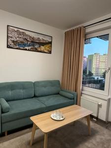 a living room with a green couch and a coffee table at Cozy Modern Apartment, 20 mins to Center in Prague