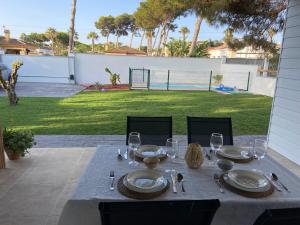 a table with plates and wine glasses on a patio at Mi Huerto, Casa con piscina, en la Barrosa in Chiclana de la Frontera