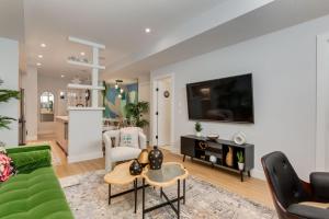 a living room with a green couch and a tv at Santuario Kensington - Inner City Escape in Calgary
