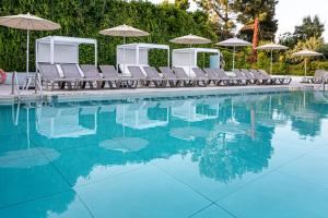 a swimming pool with chairs and umbrellas at Hotel Silgar 92 in Sanxenxo