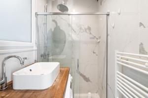 Un baño blanco con lavabo y ducha. en Arc de Triomphe Magnifique appartement, en París