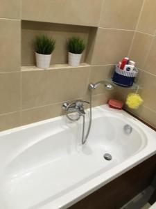 a white bath tub with a faucet and plants at Apartament Jantarowa in Gdynia