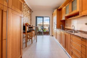 a kitchen with wooden cabinets and a table with a view at Casa Palmeira in Lagos