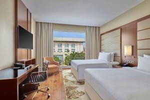 a hotel room with two beds and a desk at Courtyard by Marriott Kochi Airport in Nedumbassery